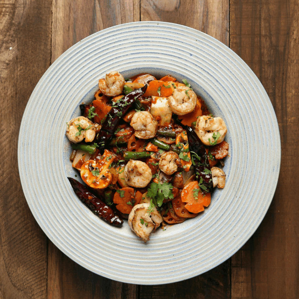 L'immagine mostra una pietanza composta da gamberi, verdure, erbe aromatiche e peperoncino, perfetta per i segni d'acqua a tavola, in particolare per lo Scorpione