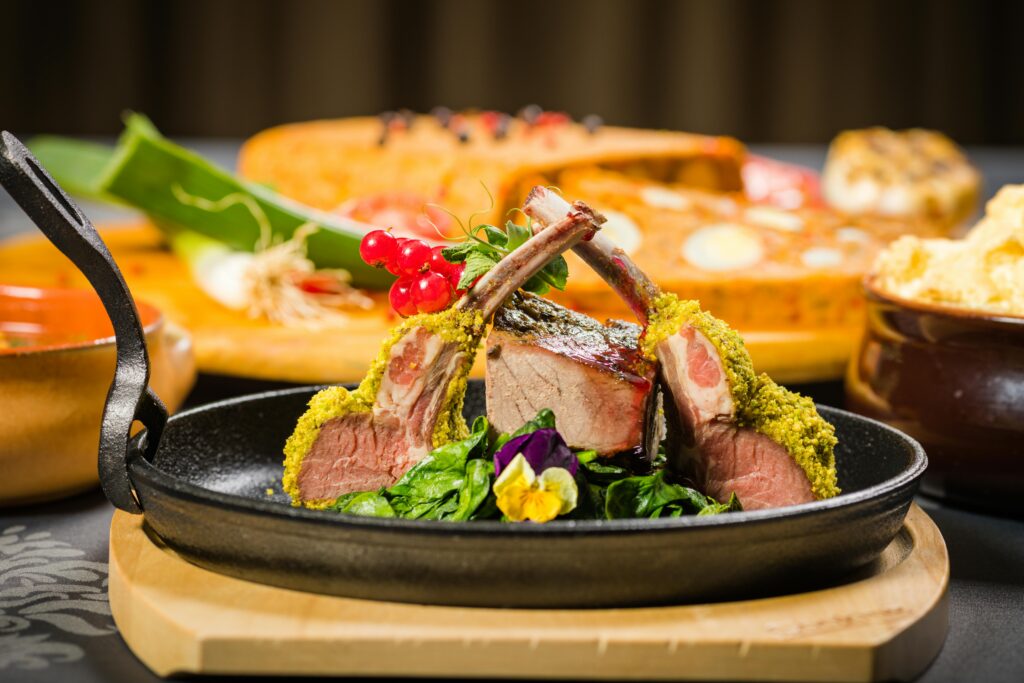 L'immagine mostra una pietanza a base di costolette di agnello con panatura al pistacchio e fiori eduli, perfetta per i segni d'aria a tavola